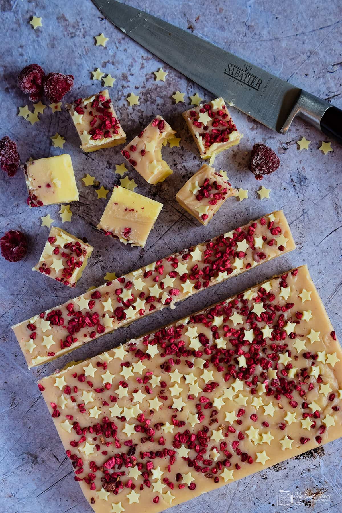 slab of raspberry and white chocolate fudge in the process of  being cut into pieces.