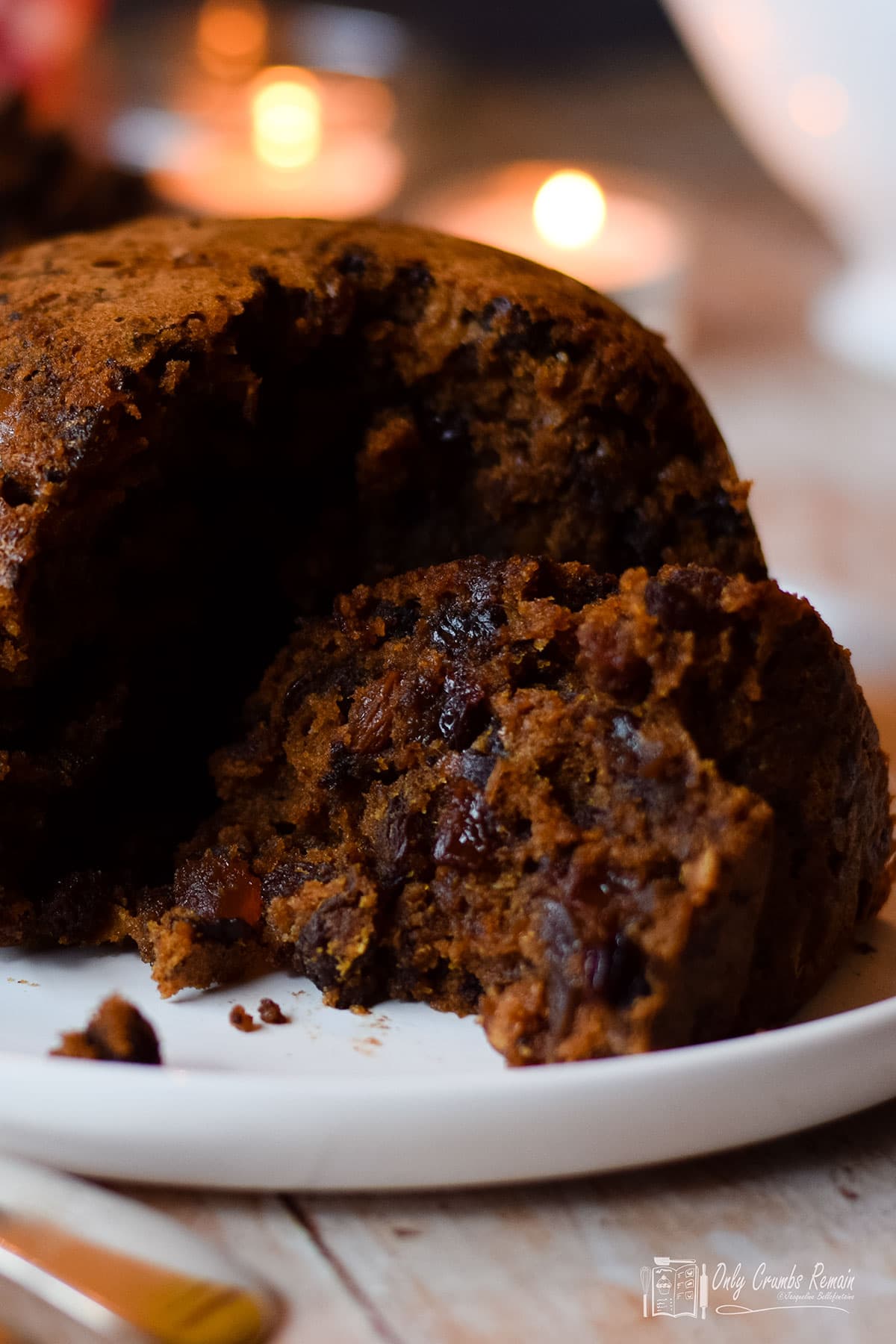 Chocolate orange Christmas pudding with slice lying on its side on the serving plate.