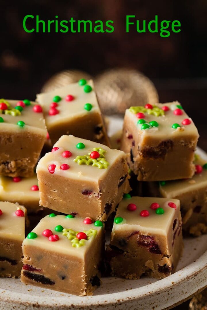 Pile of Christmas fudge decorated with sugar holly sprinkles and red and green sugar balls.