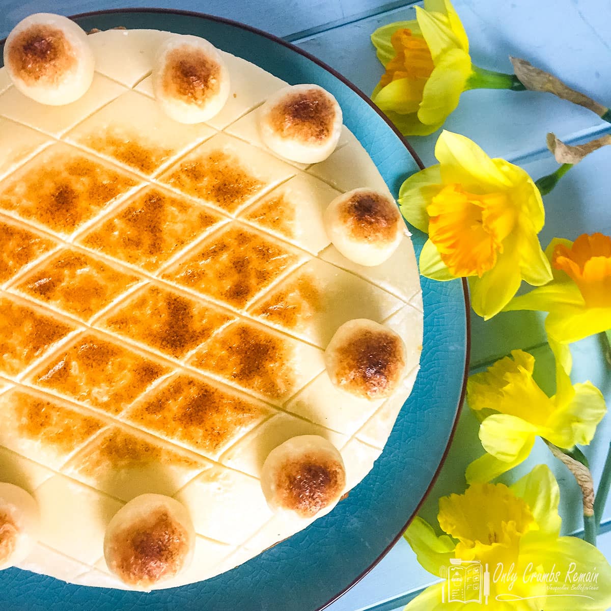 traditional simnel cake on a plate surrounded by daffodils