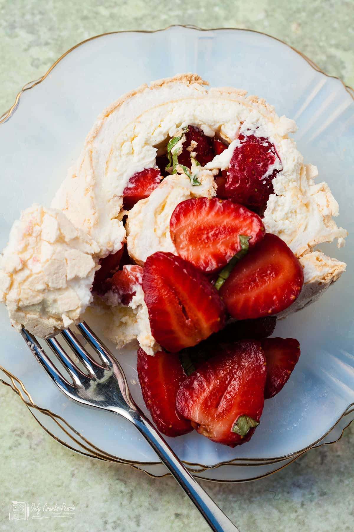 slice of meringue roulade on a serving plate with a fork breaking into the meringue.