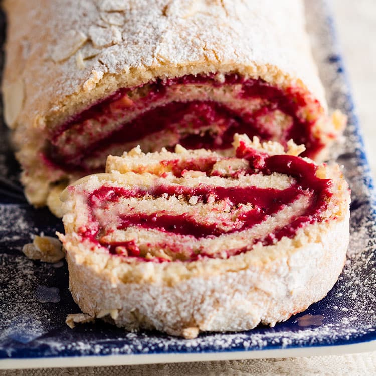 Almond and blackcurrant roulade with slice laying down in front.