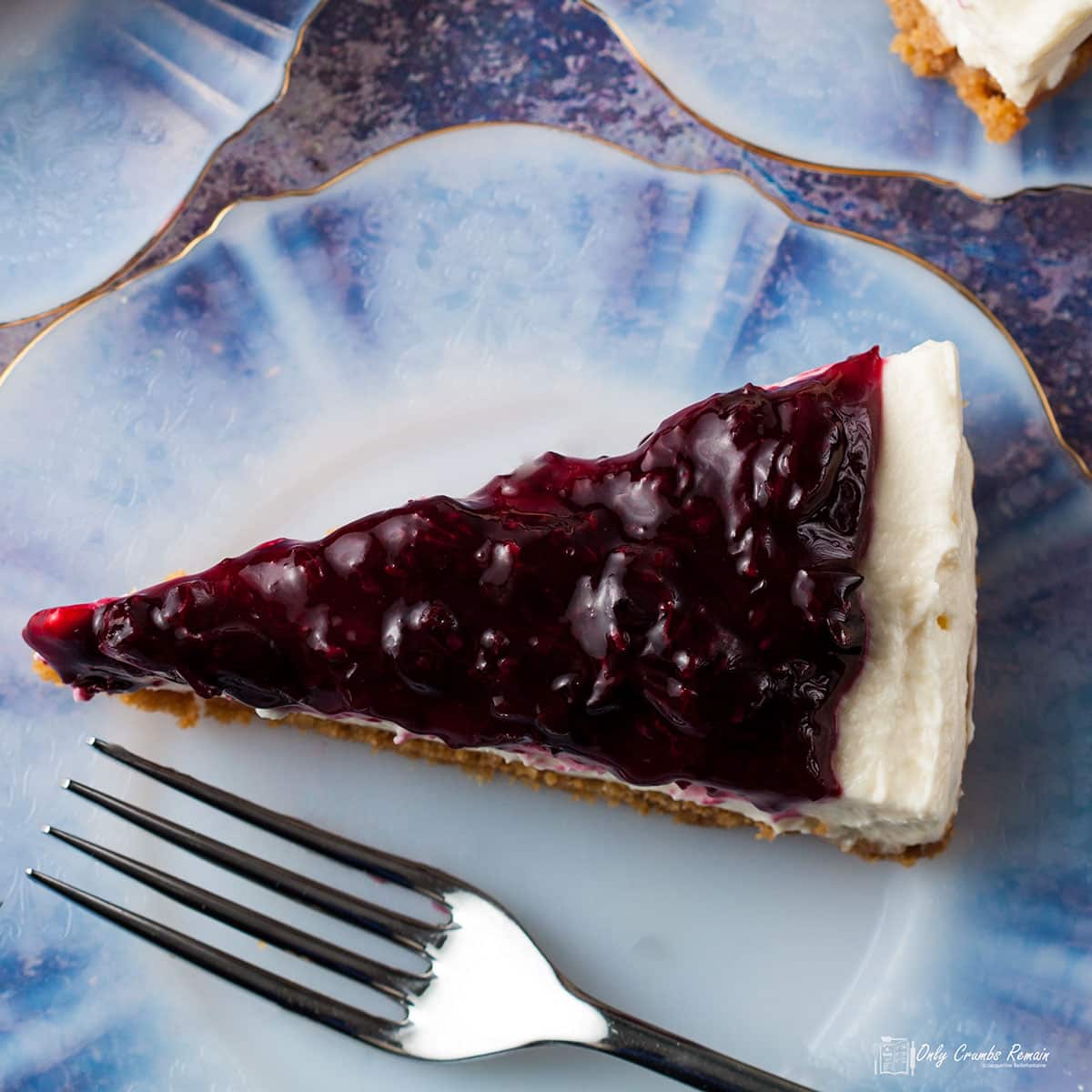 slice of blackcurrant cheesecake on a plate with a fork.