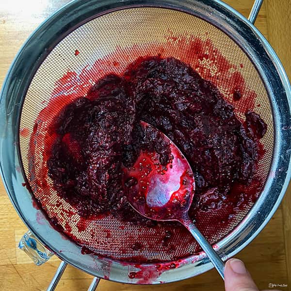 pushing blackcurrant through a sieve.