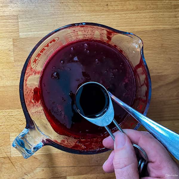 adding cassis to jug of blackcurrant puree.
