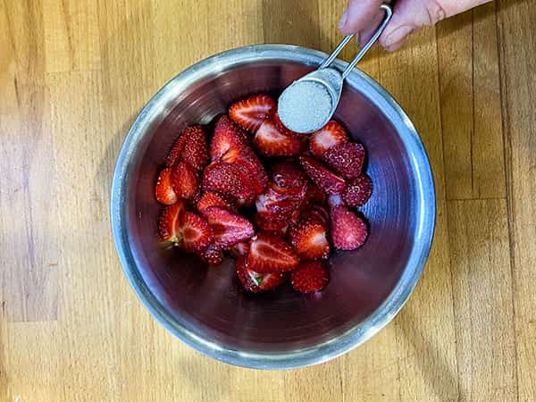 adding the sugar to the strawberries.