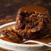 Sticky toffee pudding on plate with a spoonful removed.