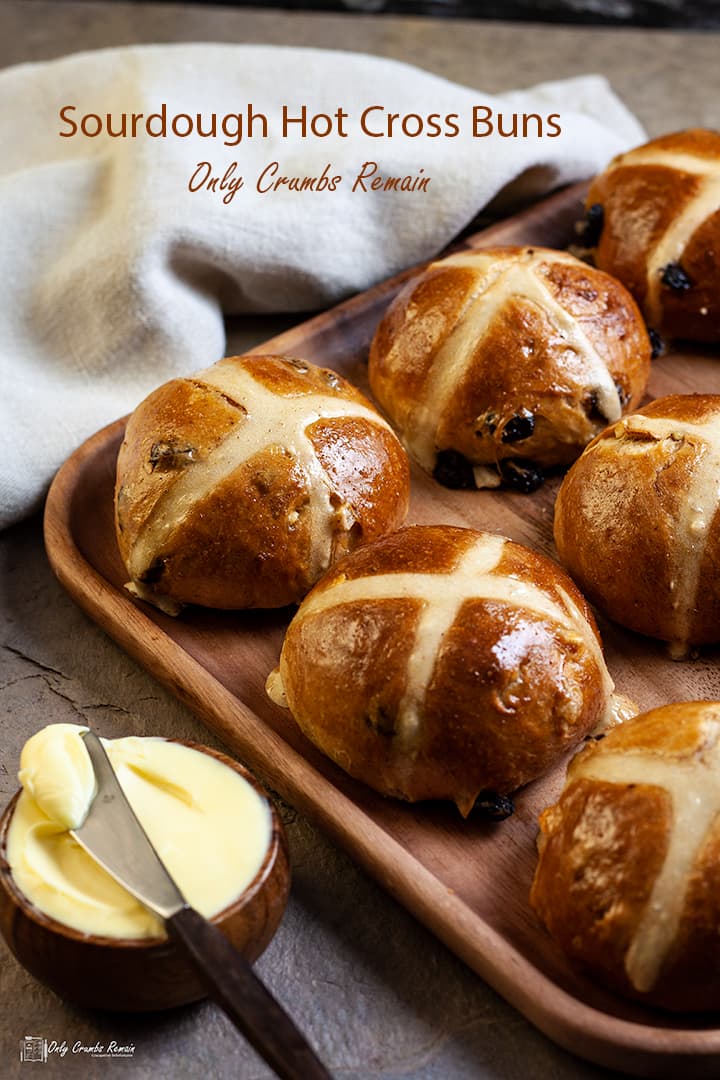 sourdough hot cross buns on a wodden tray with bowl of butter in front.
