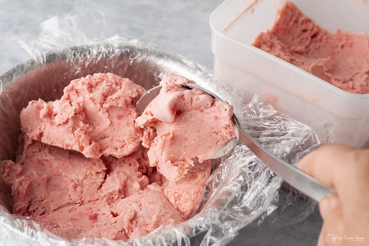 packing ice cream into a bowl lined with cling film.