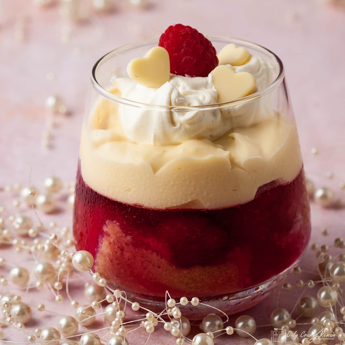 mini raspberry and white chocolate trifle in a glass with beads around the base of glass.