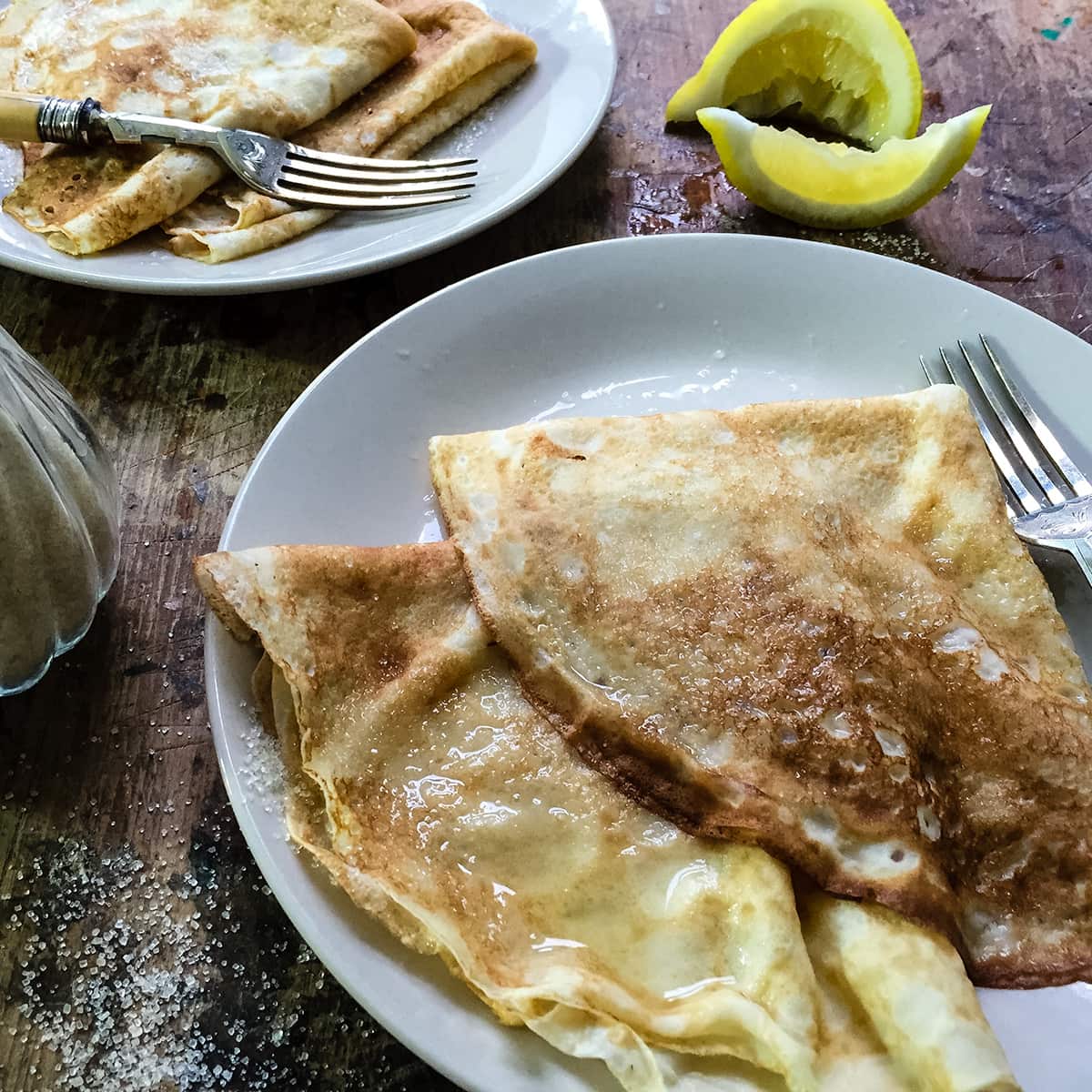 two english pancakes folded into triangles on plate with fork.