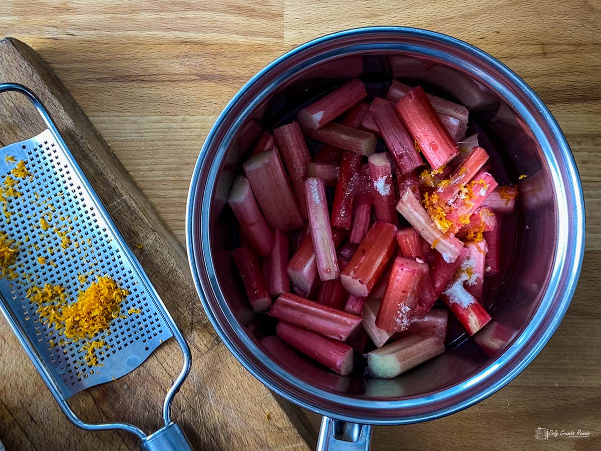 prepared rhubarb in pan with orange zest on grater by the side.