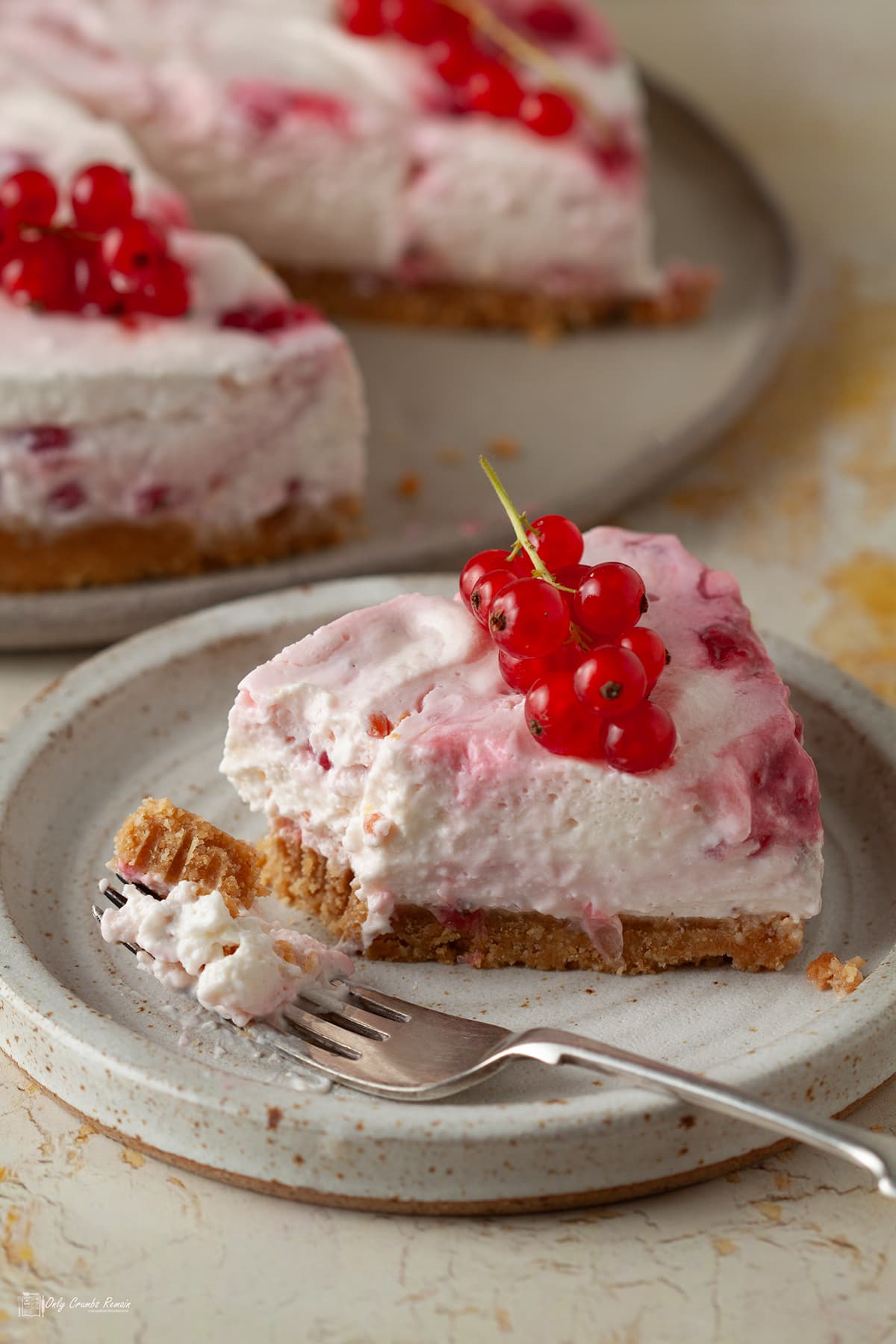 slice of redcurrant cheesecake on tea plate broken into with a cake fork.