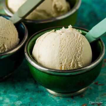 Green sliver rimmed bowl with single scoop of gooseberry ice cream and two bowls behind.