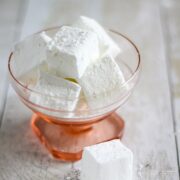 pink glass dish of gin and tonic marshmallows with one marshmallow beside the dish.